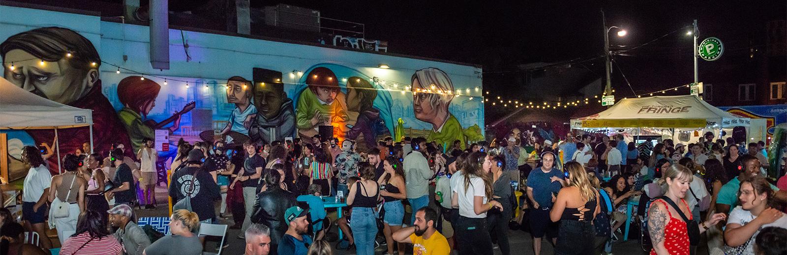 Patrons hang out at the Fringe patio at night, with string lights lighting up the space
